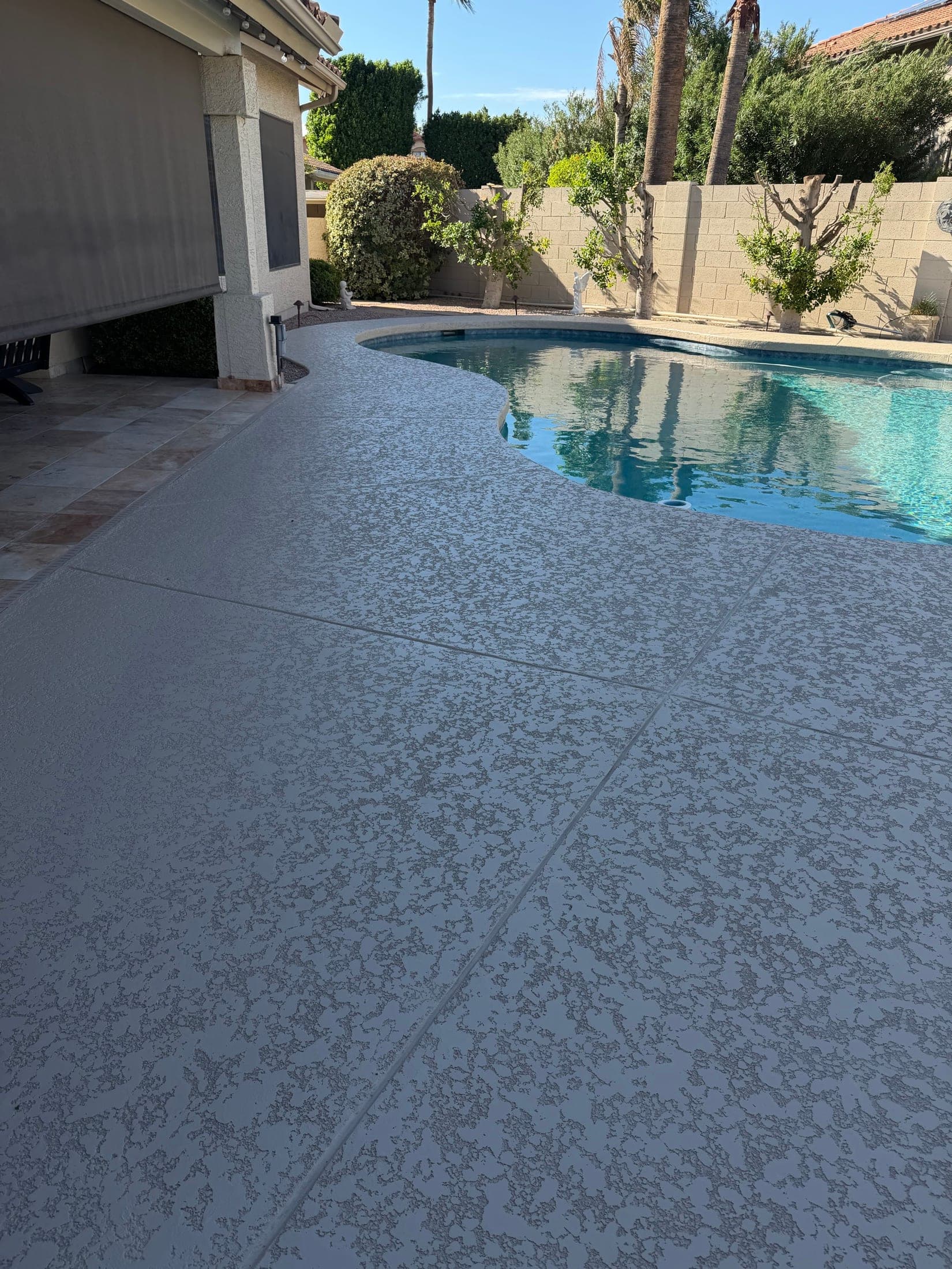 Gray knockdown cool deck resurfacing around a curved backyard pool