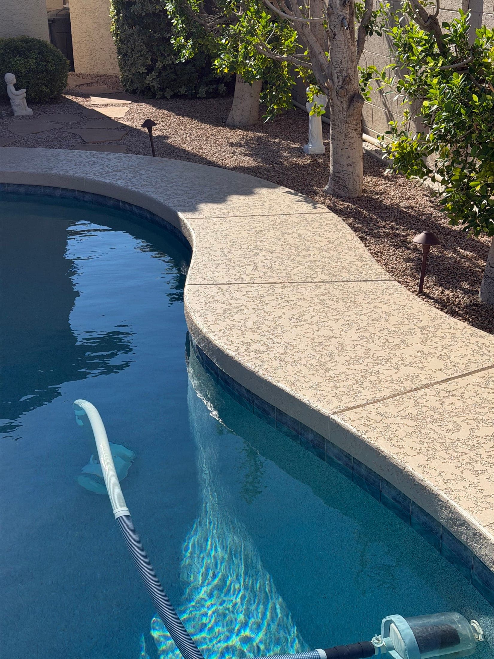 Resurfaced tan cool deck coping along a curved pool