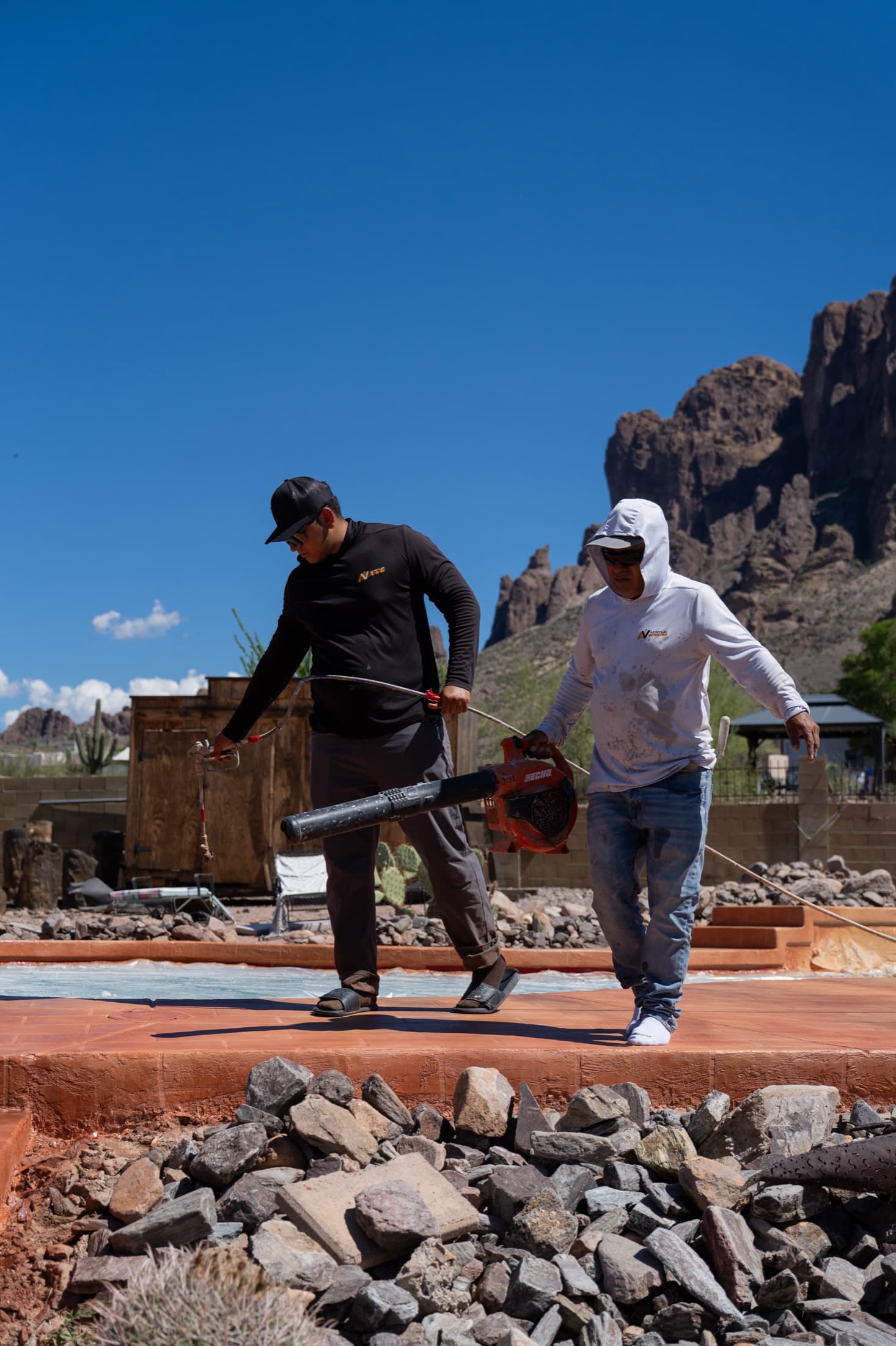 Acrylic Valley crew sealing a resurfaced pool deck with an Arizona mountain backdrop
