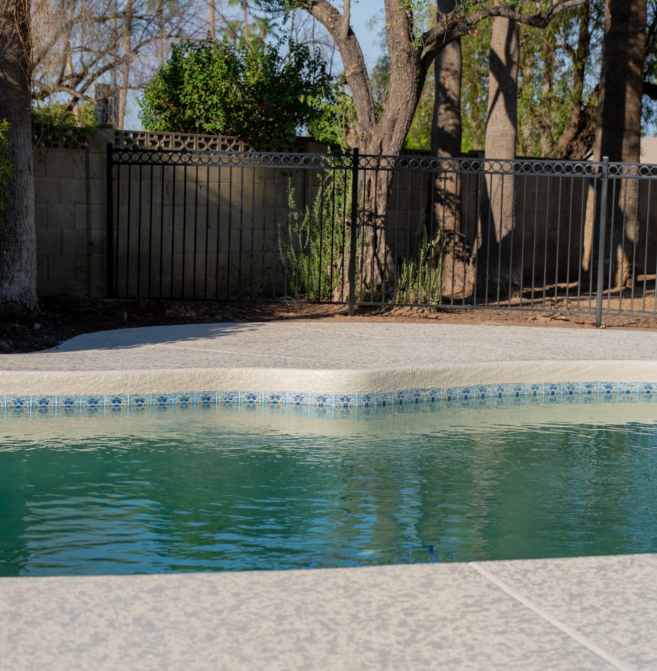 Cool deck resurfaced pool patio with decorative tile coping