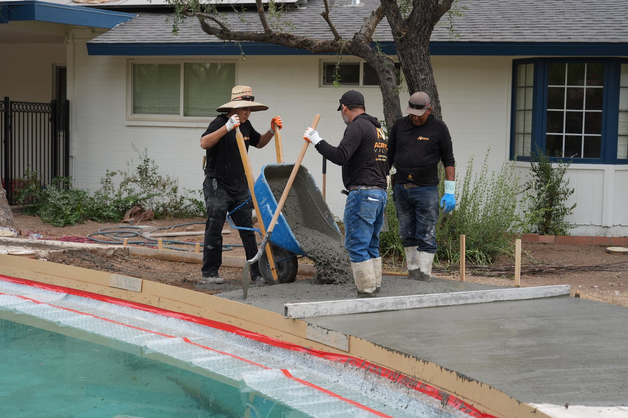 Acrylic Valley crew pouring new concrete from a wheelbarrow
