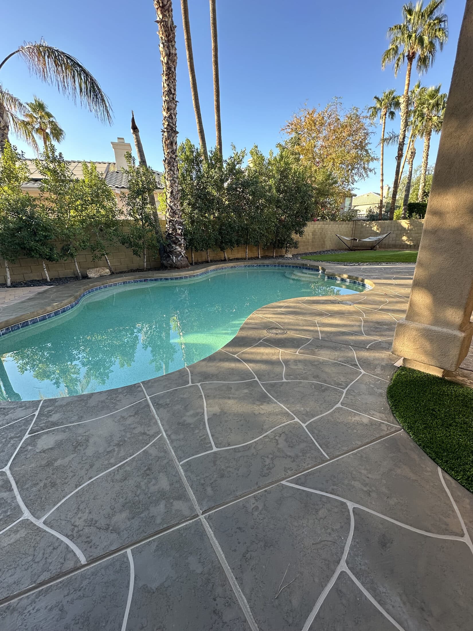 Gray flagstone-pattern stamped concrete overlay pool deck